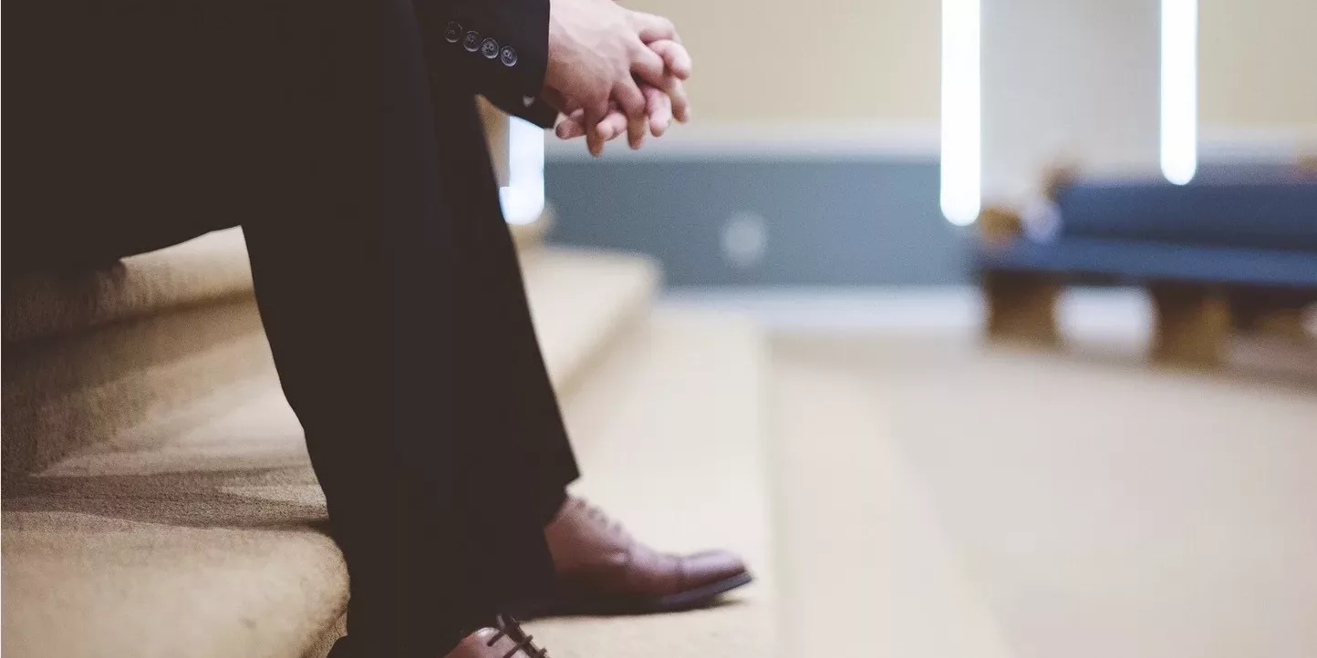 Quand le leader prend le temps de réfléchir Homme assis sur un escalier, en tenue formelle, incarnant une posture humble et réfléchie, symbole de leadership conscient et d’introspection managériale.